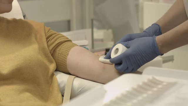 Close Up - Female Nurse with latex gloves put gauze bandage  and cotton to a woman's arm patient