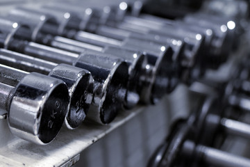 Close up of small weight metallic dumbbells in a row.