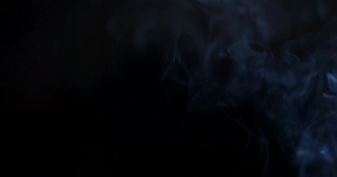 Cloud of smoke or vapor rising against a black background in slow motion