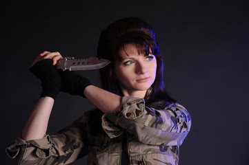 brunette in a military-colored jacket with a knife in her hands in the studio