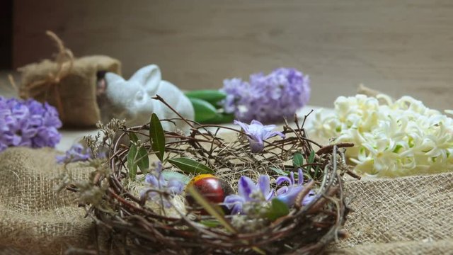 Child's hand puts festive colored egg in in the Easter nest