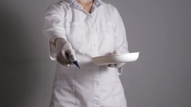 Female doctor giving medication. Young medical professional gives digital thermometer taking from kidney dish. Slow motion.