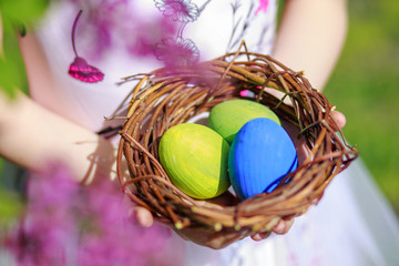 Girl holding a basket with Easter eggs. Tchild gathered on the street in the spring of eggs from the Easter Bunny.