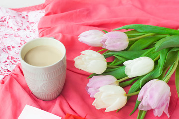 Obraz na płótnie Canvas Bouquet of tulips with a mug of coffee and a gift in a red box on a pink cloth. International Women's Day, Valentine's Day, Mother's Day. Selective focus.