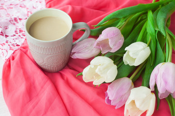 Fototapeta na wymiar Bouquet of tulips with a mug of coffee and a gift in a red box on a pink cloth. International Women's Day, Valentine's Day, Mother's Day. Selective focus.
