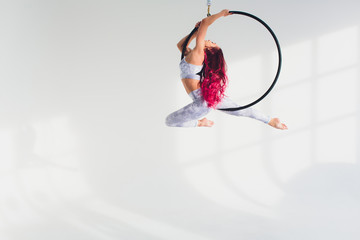 young redhead woman performs acrobatic elements in the air ring on a white background. © Евгений Вершинин