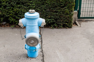 Fototapeta na wymiar Blue metal vintage fire hydrant on asphalt road at city street