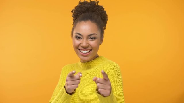 Pretty smiling black lady showing I choose you gesture into camera, close up
