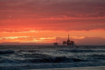 sunset at the beach with oil rig