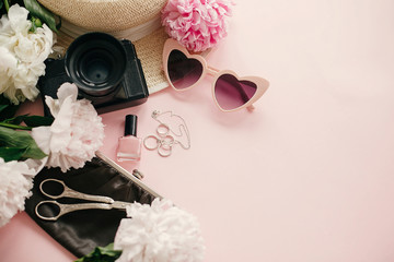 Obraz na płótnie Canvas Stylish girly flat lay with pink peonies, photo camera, retro sunglasses, jewelry, nail polish, hat, purse on pastel pink paper with copy space. International Women's Day. Hello spring