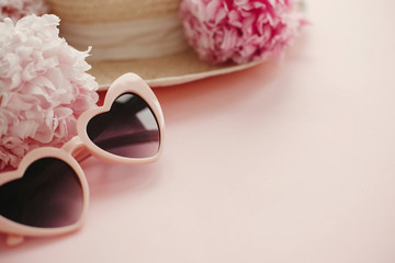 Obraz na płótnie Canvas Summer vacation concept. Stylish girly pink retro sunglasses, white and pink peonies, straw hat on pastel pink paper with copy space. Hello spring concept. International Women's Day