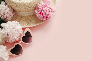 International Women's Day. Stylish girly pink retro sunglasses, white and pink peonies, straw hat on pastel pink paper with copy space. Hello spring concept. Summer vacation flat lay.