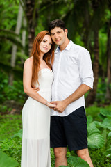Fototapeta premium A young couple is embracing against the backdrop of a green rainforest