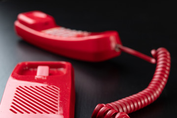 Old analog telephone. Red phone on a wooden dark table.