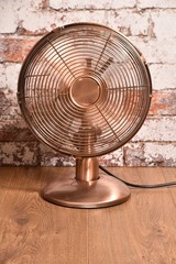 Picture of old style ( brass or copper effect ) electric fan - ventilator with moving blades.