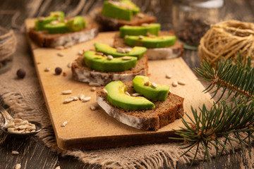 bruschetta with chopped avocado, olive oil, and seeds of seeds and sesame. Background for design. Healthy vegetarian breakfast on wooden background, healthy nutrition and healthy food.
