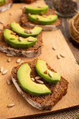 bruschetta with chopped avocado, olive oil, and seeds of seeds and sesame. Background for design. Healthy vegetarian breakfast on wooden background, healthy nutrition and healthy food.