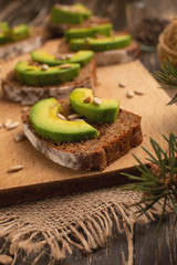 bruschetta with chopped avocado, olive oil, and seeds of seeds and sesame. Healthy vegetarian breakfast on wooden background, healthy nutrition and healthy food.