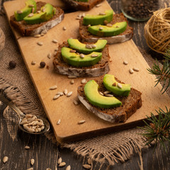 bruschetta with chopped avocado, olive oil, and seeds of seeds and sesame. Background for design. Healthy vegetarian breakfast on wooden background, healthy nutrition and healthy food.