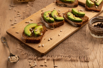 bruschetta on a wooden background with avocado and seeds of shooting, olive oil. Healthy vygityryanskoye food, tasty and healthy food