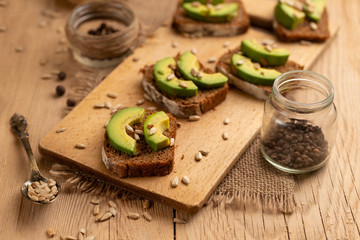 bruschetta on a wooden background with avocado and seeds of shooting, olive oil. Healthy vygityryanskoye food, tasty and healthy food