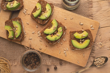 bruschetta on a wooden background with avocado and seeds of shooting, olive oil. Background for design, healthy and clean nutrition. Vegan food