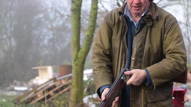 Sports clay pigeon shooting. Adult male hunter reloads the cartridge and smoke comes out the shotgun after firing. Slow motion.