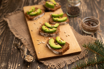 ciabatta toasts, bruschetta with chopped avocado, olive oil, and seeds of sesame and sesame. Healthy vegetarian breakfast on wooden background