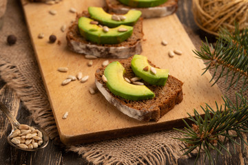 ciabatta toasts, bruschetta with chopped avocado, olive oil, and seeds of sesame and sesame. Healthy vegetarian breakfast on wooden background
