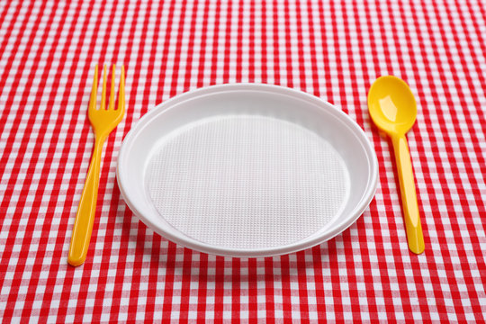 Table setting with plastic dishware on plaid fabric