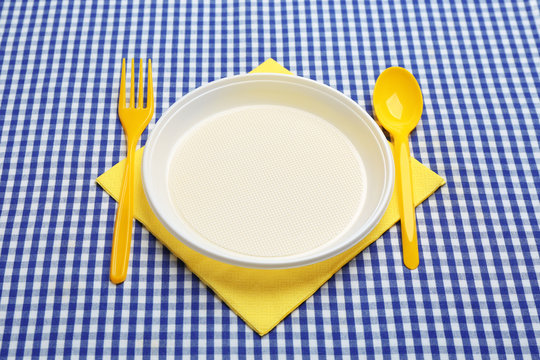 Table setting with plastic dishware on plaid fabric