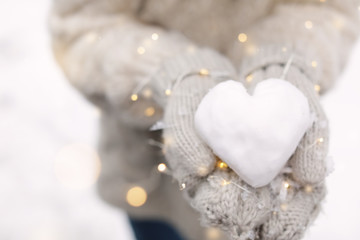 Woman holding Christmas lights and heart made of snow, closeup