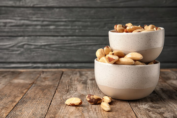 Bowls with tasty Brazil nuts on wooden table. Space for text