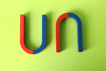 Red and blue horseshoe magnets on color background, top view