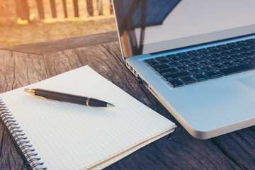 Business accessories (notebook, magnifier, calculator, planchette, tablet, fountain pen, notebook, glasses) and graphics, tables, charts on a wooden office desk. Soft focus