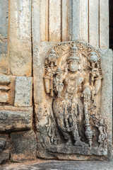 Belavadi, Karnataka, India - November 2, 2013: Veera Narayana Temple. Closeup of Brown stone Sculpture of Lord Vishnu set against wall outside entry hall to sanctuary . Partly damaged.