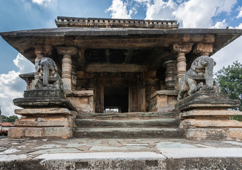 Belavadi, Karnataka, India - November 2, 2013: Veera Narayana Temple. Entrance hall, street side, to the sanctuary grounds show two elephant statues and a pillared structure. Blue sky with white cloud