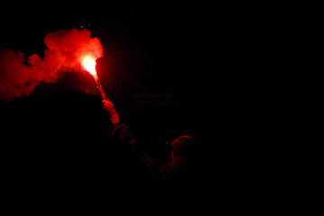 Guy holding a red bright torch at night