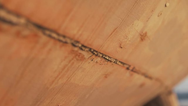 Slider shot of rustic gritty old mastic sealant in between carvel constructed Sapele timber planking on old sailing boat