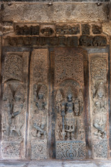 Belur, Karnataka, India - November 2, 2013: Chennakeshava Temple. Brown wall stone panel sculpture of Lord Vishnu surrounded by his two consorts Devi Lakshmi and Devi Bhu with Shilabalika women. On si