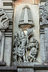 Belur, Karnataka, India - November 2, 2013: Chennakeshava Temple. Gray wall stone panel sculpture of Lord Vishnu surrouned by his two consorts Devi Lakshmi and Devi Bhu. Side of temple.
