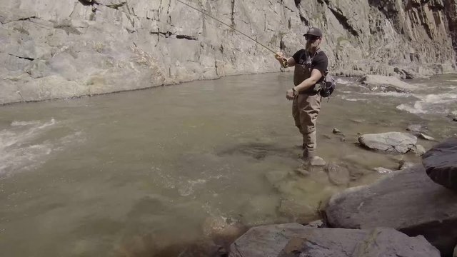 A fly fisherman casts forward upstream in a roaring river.