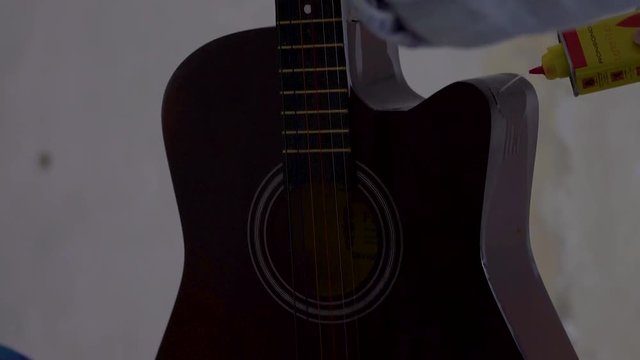 Closeup of a man's hand poring gasoline on the guitar.