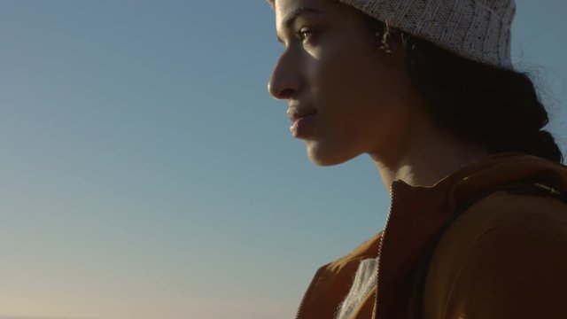 Close up of african female enjoying the view from mountain top. Female in warm jacket and knitted cap standing outdoors.