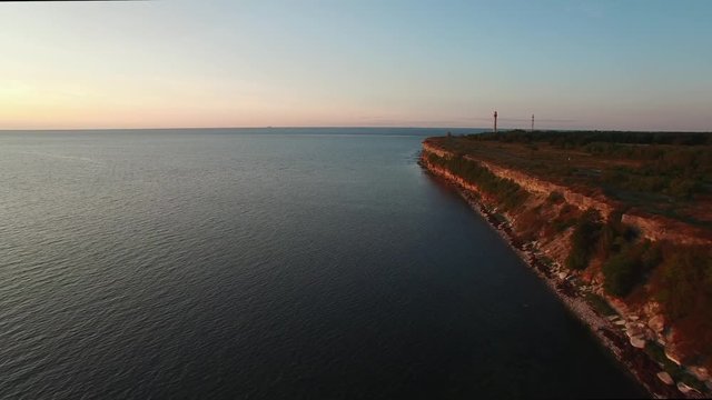 Top aerial drone view of high cliff on the Pakri Peninsula on the Baltic sea in Estonia.  The glare of the sun in the lighthouse reflector.