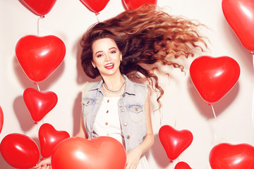 Valentine Beauty girl with red air balloons laughing, on white background. Beautiful Happy Young woman. Womans day. Holiday party, dance. Joyful model posing, having fun, celebrating Valentine`s Day.