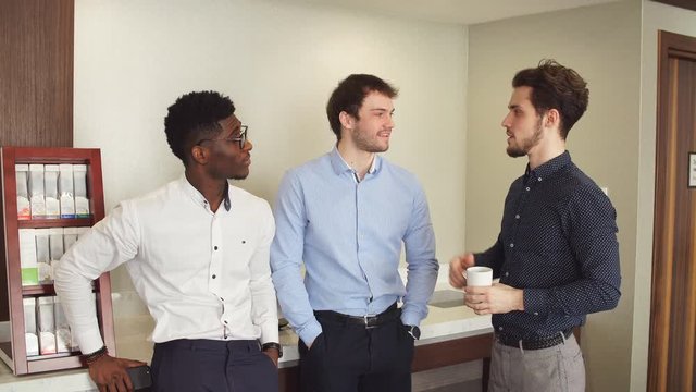Three awesome office workers having fun during the coffee break. Colleagues telling jokes to each other