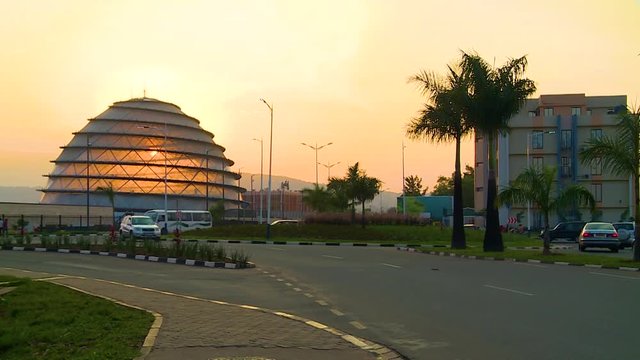 Wide view of a Kigali roundabout at sunset with the convention center dome in front of the sun, Rwanda.