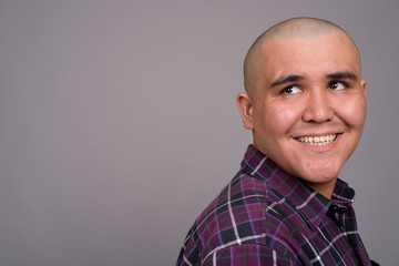 Obraz premium Young bald Asian businessman against gray background