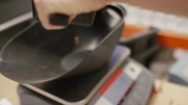Fresh roasted coffee beans being poured into a container ready for weighing, in slow motion